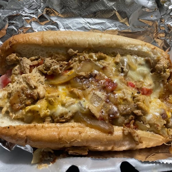 Cheesesteak sandwich from Tastee Buddies, filled with meat, melted cheese, onions, and peppers.